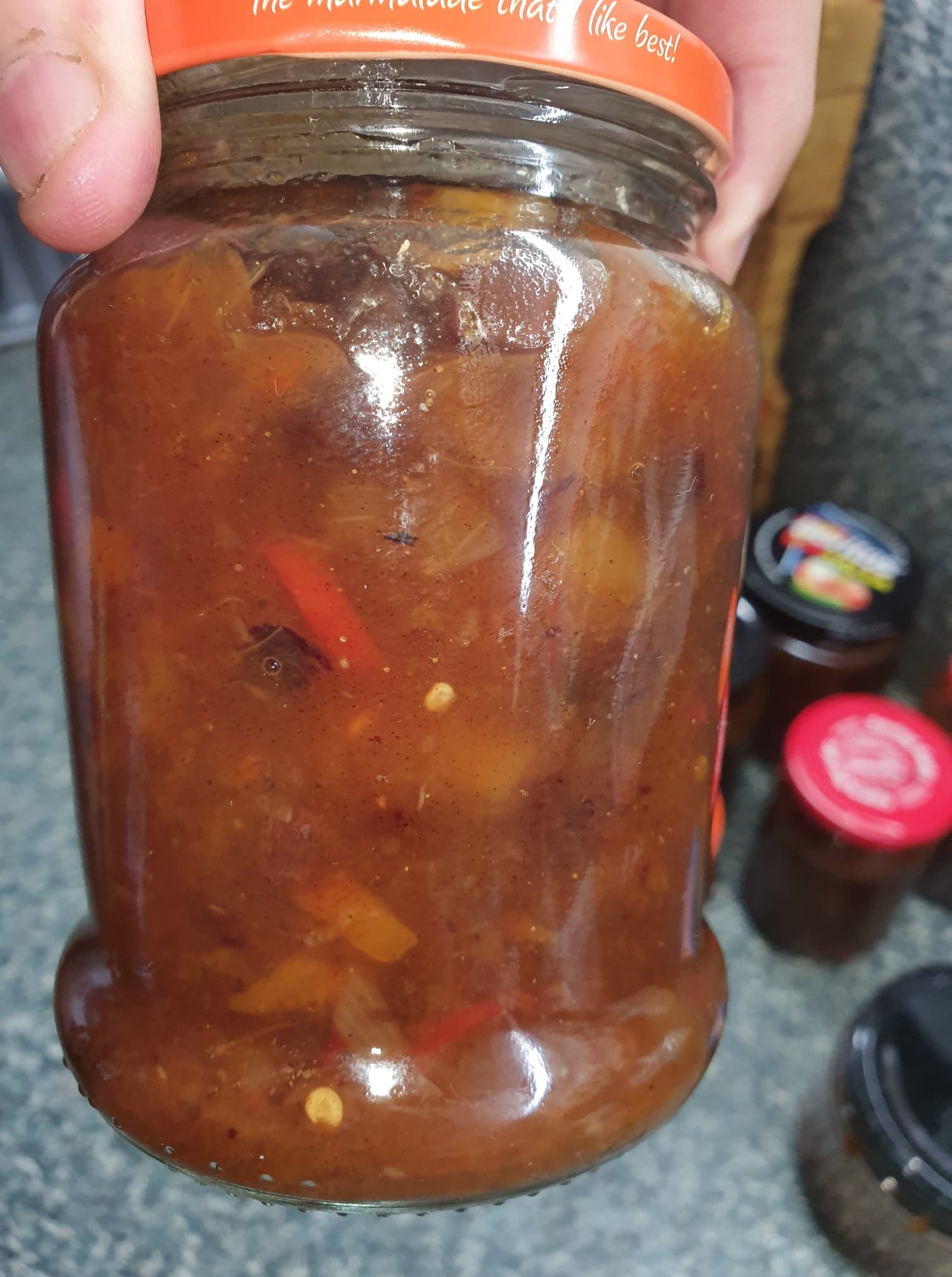 Rhonda's Spicy Mango Chutney in a glass jar with a spoon